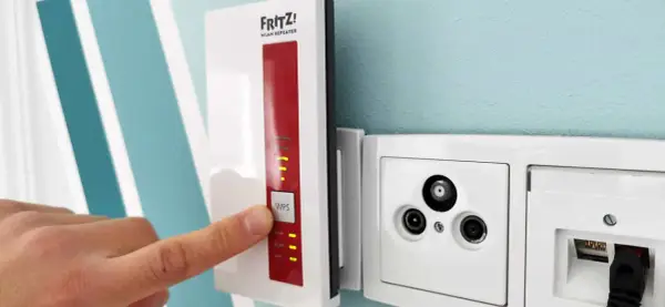 Fritz! WLAN Repeater verbessert das Signal, um **WLAN durch Betondecke** zu leiten. Ein Finger drückt auf die WPS-Taste.